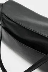 Bolso de hombro de piel color negro, con diseño estructurado, solapa superior y correa ajustable para el hombro.