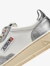 Zapatillas urbanas Autry Medalist Low, de cuero blanco con detalles plateados, cordones de algodón y suela de goma color crema.