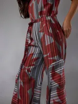 Mono de lino mezcla con estampado vegetal en tonos rojos, grises y blancos, de manga corta, escote en V y piernas amplias con cinto incorporado para ajustar la cintura.