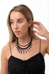 Collar doble de diseño vanguardista, compuesto por una cadena superior de cuentas pequeñas y una inferior con colgantes en forma de bastones alargados, todo en color negro. Incluye cadena de acero quirúrgico para ajuste.