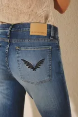 Jean de corte oxford en color azul oscuro con efecto de lavado localizado. Presenta bolsillos traseros con detalle de alas bordadas en hilo negro y etiqueta de marca en la cintura.
