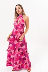 Vestido largo fucsia con estampado abstracto, cuello halter con abertura en forma de lágrima y volados en la falda.