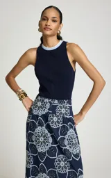 Musculosa azul marino de punto acanalado, con escote redondo ribeteado en celeste y blanco, de corte ajustado y sisas amplias.