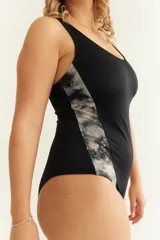 Malla enteriza deportiva negra con corte diagonal y estampado abstracto en los laterales. Espalda estilo nadadora.