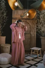 Camisa de lino negra con bordados dorados en forma de árbol o palmera estilizada. Presenta cuello camisero, botones frontales dorados y pliegues verticales en la parte inferior delantera.