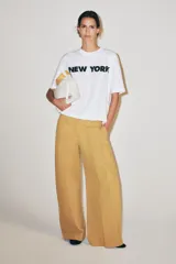 Remera oversize blanca de algodón con cuello redondo, manga corta y estampa con la inscripción 'NEW YORK' en color negro en el frente.