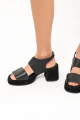 Sandalias negras de cuero con plataforma y taco cuadrado forrado. Presentan doble tira ancha sobre el empeine y tira con hebilla al tobillo.