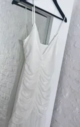 Vestido blanco de breteles finos, con escote en V y falda midi con volados.