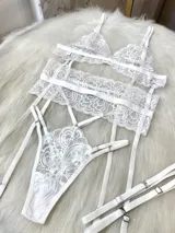 Conjunto de lencería de cuatro piezas en color blanco, confeccionado en encaje con diseño floral. Incluye bralette triangular, tanga de tiro alto con tiras ajustables, portaligas integrado y ligas para las piernas.