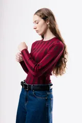 Top de tejido de punto ajustado al cuerpo, con diseño de rayas verticales en tonos bordó y rojo. Presenta cuello redondo y mangas largas.