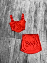 Conjunto de dos piezas confeccionado en tela satinada color azul vibrante. Incluye un top tipo corset con escote cuadrado y una minifalda ajustada de tiro alto.