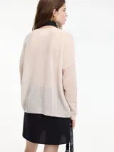 Sweater de punto fino color gris claro, con cuello en V y mangas largas. El tejido parece ser ligeramente transparente o muy liviano.