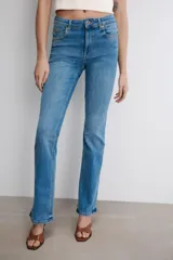 Jeans de tiro medio con corte bootcut y ajuste slim. Presenta diseño de cinco bolsillos, trabillas en la cintura y cierre frontal con cremallera y botón. Incluye detalle de pespuntes marcados a contraste.