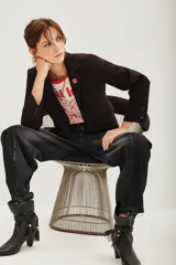 Saco de corte sastre entallado, color negro, con solapas clásicas, cierre frontal de un botón y mangas largas con detalle de botones en los puños.