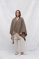 Ruana de lana 100% sin teñir en color marrón con textura jaspeada y terminación de flecos en color crudo.
