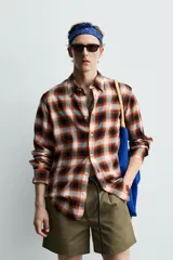 Camisa de corte regular fit confeccionada en tejido fluido de algodón y viscosa. Presenta un diseño de cuadros, cuello solapa, manga larga con puños abotonados, bolsillo en el pecho y cierre frontal con botones.