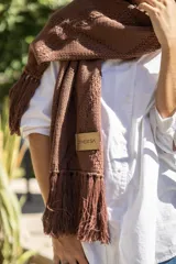 Bufanda tejida en color marrón con diseño de rombos en relieve y terminación con flecos en los extremos. Incluye una etiqueta de cuero sintético con la marca Diversa.