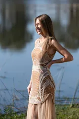 Vestido largo sin mangas, con base de seda natural y diseño bordado a mano con canutillos y paillettes en tonos mostaza y beige, con falda larga de tul transparente.