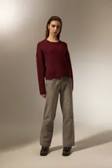 Sweater de punto negro con destellos de lurex, cuello redondo a la base y mangas largas con puños ajustados.