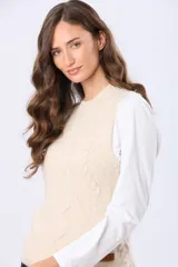 Chaleco tejido color beige, con cuello redondo y diseño de ochos en el frente.