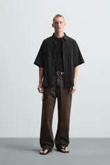 Camisa de manga corta con cuello solapa, confeccionada en tejido de mezcla de lyocell con textura de efecto arrugado y cierre frontal de botones.