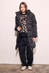 Tapado negro largo con capucha, diseño capitoneado y cierre frontal con botones dorados.