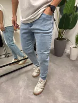 Jean de corte skinny en color azul claro, confeccionado en denim con elastano. Presenta un diseño clásico de cinco bolsillos y cierre frontal con botón y cremallera.