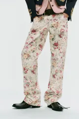 Jeans rectos de tiro medio con estampado floral multicolor sobre base blanca, trabillas para cinto, bolsillos delanteros y cierre frontal con cremallera y botón metálico.