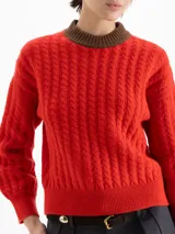 Sweater de punto con diseño de ochos y rayas verticales en color rojo. Presenta cuello redondo, puños y cintura en contraste de color marrón oscuro.