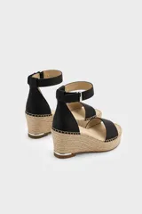 Sandalias de tacón en cuña forrada en yute trenzado, con capellada de cuero negro, tira en el talón y tira ajustable al tobillo con hebilla metálica.