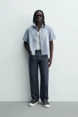 Camisa de corte boxy fit confeccionada en denim ligero de algodón. Presenta cuello solapa, manga corta y cierre frontal con botones. Diseño con efecto lavado.