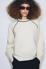 Jersey de punto de manga larga con cuello redondo, diseño en color azul marino con detalles de vivo en color blanco en el cuello y las costuras de las mangas.