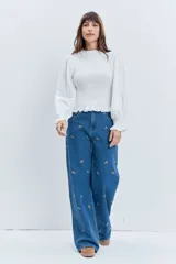 Jean de corte wide leg en color azul medio, con diseño de pequeños bordados dispersos en toda la prenda. Presenta cierre frontal con botón y bolsillos laterales.