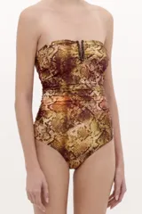 Malla enteriza strapless con estampado de serpiente en tonos marrones y dorados, con detalle de abertura en el escote bordeada con cuentas oscuras y fruncidos laterales.
