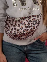 Riñonera tipo bandolera con estampado animal print, correa de algodón color beige y etiqueta con logo de la marca.
