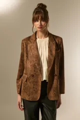 Blazer de poliéster con estampado animal print en tonos marrones y negros, de corte holgado, con cuello solapa y cierre frontal de doble botonadura.