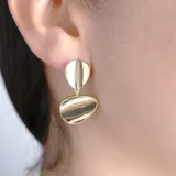 Aros colgantes dorados con dos piezas ovaladas irregulares y pulidas.