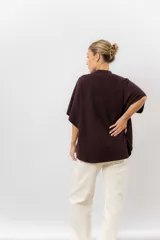 Sweater de tejido de punto color negro, con cuello semi alto y mangas cortas amplias. Presenta una silueta relajada y caída fluida.