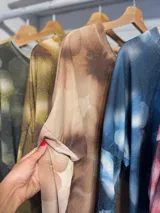 Remera de manga larga con diseño estampado de flores en tonos marrones y destellos de lurex. Presenta un corte holgado, cuello redondo y puños en color gris claro.