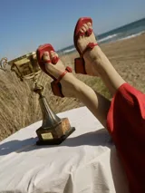 Sandalias de cuero rojo con taco cuadrado y puntera cuadrada. Presentan tiras finas adornadas con detalles de rosas en relieve sobre el empeine.