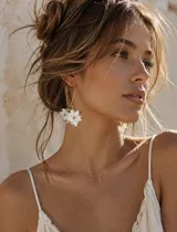 Caravanas colgantes doradas con diseño de aro alargado y dijes en forma de flores blancas con centro dorado.