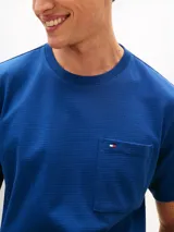 Remera de corte amplio y hombros ligeramente caídos, confeccionada en punto de malla de mezcla de algodón en color azul. Presenta cuello redondo, mangas cortas y un bolsillo de parche en el pecho con el logo de Tommy Hilfiger bordado.