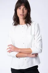 Blusa blanca de manga larga con cuello mao y cierre frontal con botones.