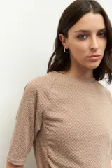 Remera negra de cuello redondo y manga tres cuartos, confeccionada en tela con textura sutil. Presenta fruncidos laterales que aportan caída y movimiento a la prenda.