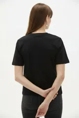 Remera de manga corta color blanco, de corte holgado con cuello redondo a la base y estampado frontal en tono bordó de un gato y un ovni en un paisaje desértico.