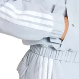 Campera bomber Adidas de corte cropped, color gris claro con las icónicas tres tiras blancas en las mangas. Presenta cierre frontal completo, cuello tipo bomber, puños y ruedo elásticos, y bolsillos laterales. Incluye el logo de la marca estampado en el pecho.