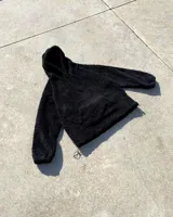 Hoodie negro de peluche con capucha, cordón ajustable y bolsillo tipo canguro.