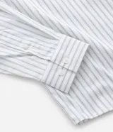 Camisa de manga larga con diseño de rayas verticales, cuello clásico y cierre frontal con botones. Confeccionada en una mezcla de algodón, poliamida y elastano, presenta una estampa gráfica en la espalda con la frase Echoes of a Restless Beat.