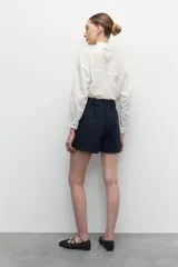 Short de tiro alto color azul marino, confeccionado en tejido tweed, con dos bolsillos frontales y cintura elástica.