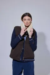 Chaleco tejido de punto color marrón con cuello de piel sintética, cierre frontal con cursor de cuero y diseño acolchado con cortes horizontales.